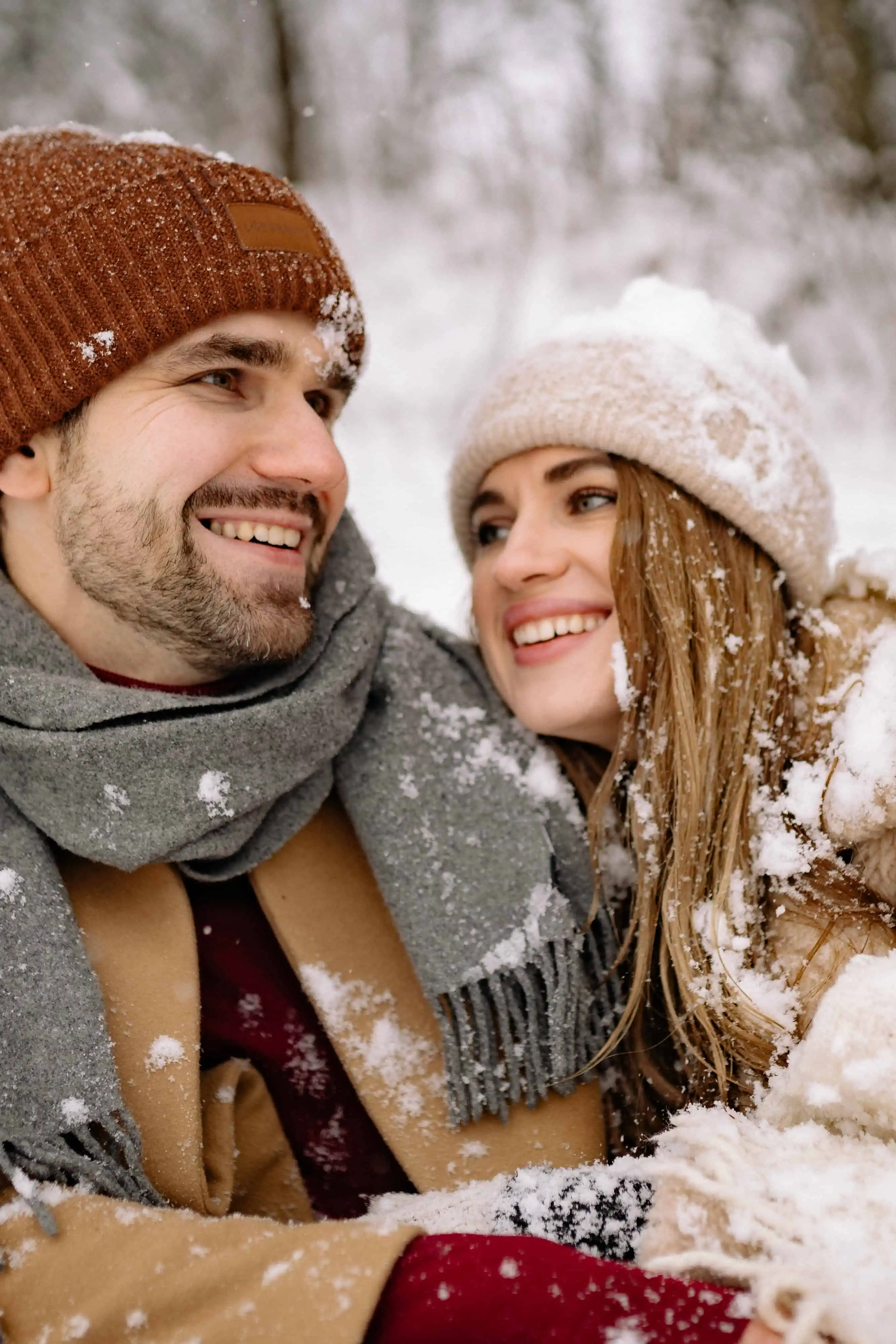 A picture of a smiling man and woman in the snow, wearing winter clothing.